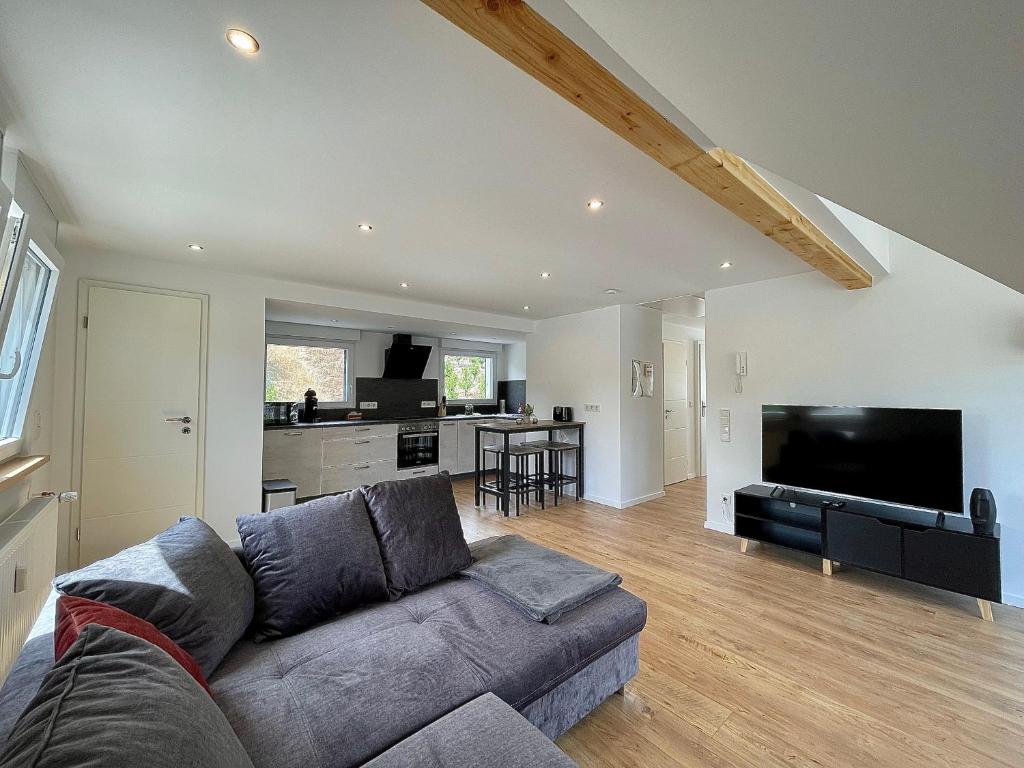 a living room with a gray couch and a kitchen at Sky Apartment, Sauna, Blick zur Mosel, großer Balkon, Kaffeemaschine, Smart TV in Zell an der Mosel