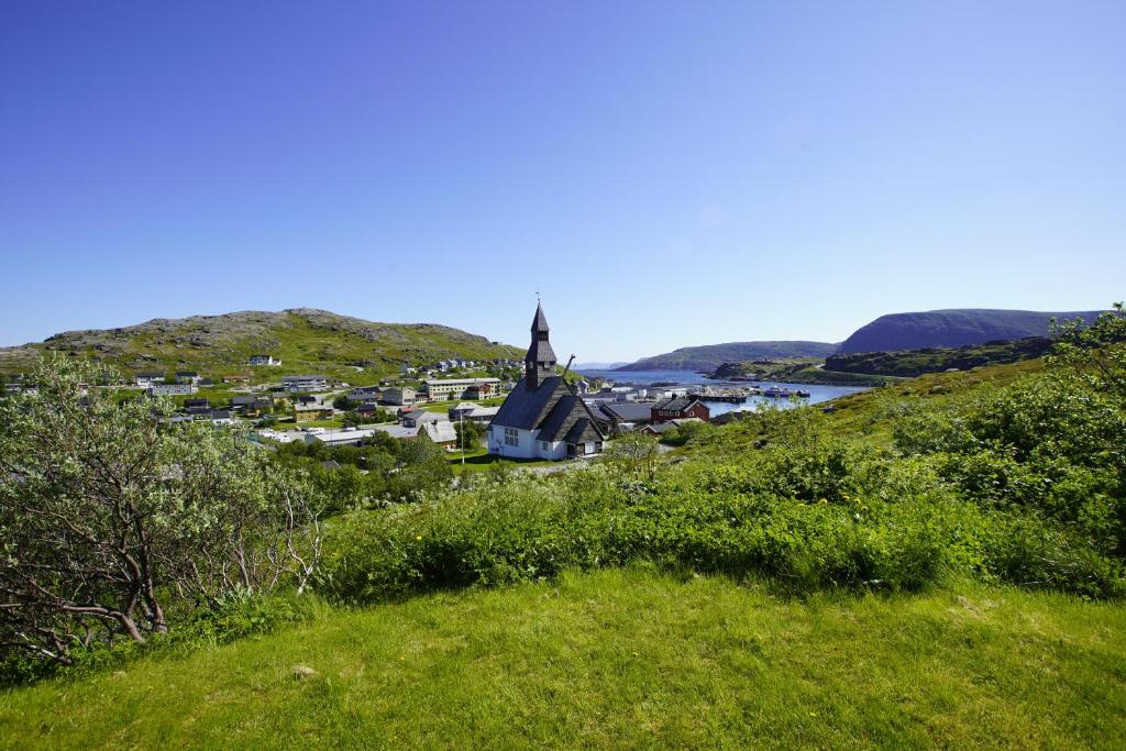 a small town on a hill with a church at Havøysund house with a beautiful view in Måsøy