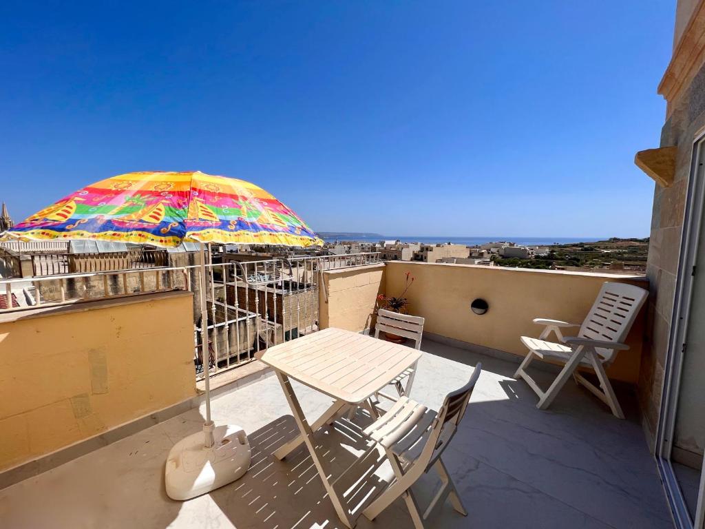 un tavolo e sedie su un balcone con ombrellone di All Nations Holiday Home a Għajnsielem