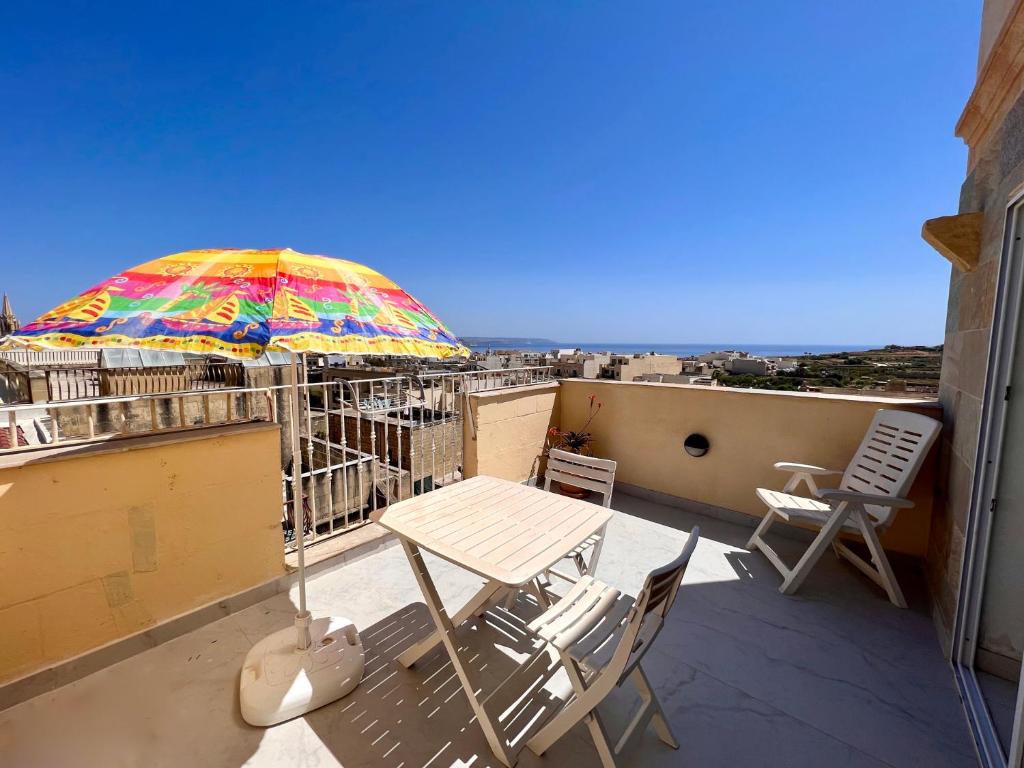 a table and chairs on a balcony with an umbrella at All Nations Holiday Home in Għajnsielem