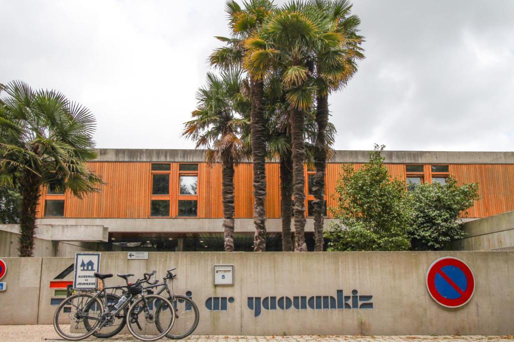 twee fietsen geparkeerd voor een gebouw met palmbomen bij AUBERGE DE JEUNESSE DU MOULIN BLANC in Brest