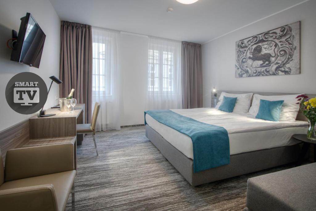 um quarto de hotel com uma cama grande e uma secretária em Hotel Páv em Praga
