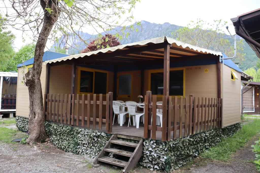 a small house with a deck with tables and chairs at Bungalow at Lake Lugano in Porlezza