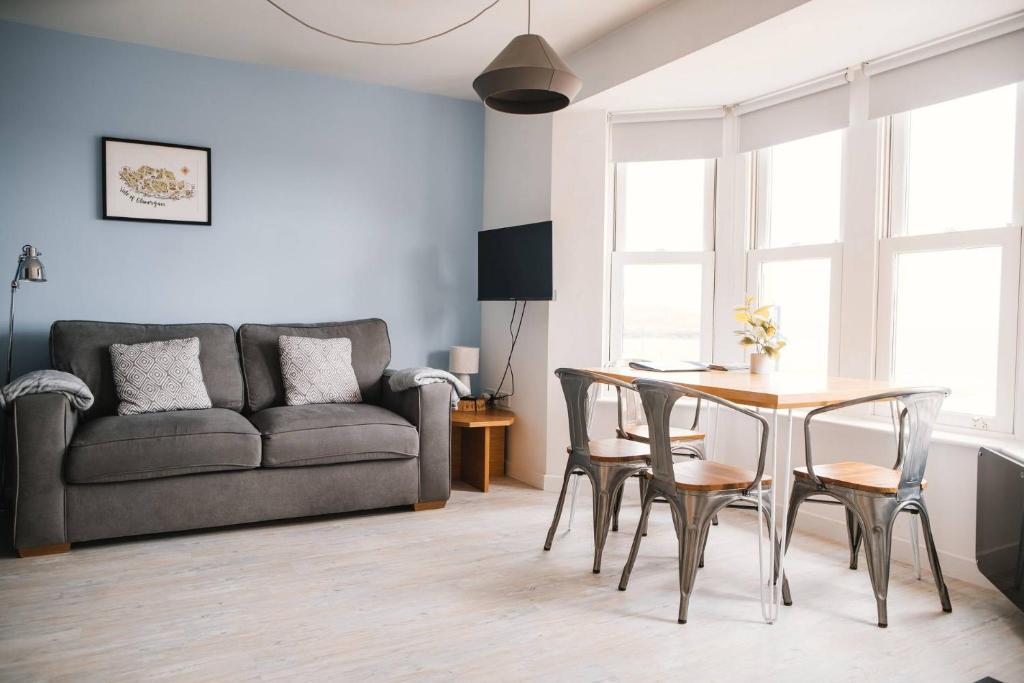 uma sala de estar com uma mesa e cadeiras e um sofá em Barry Island Beachfront Apartment - Stunning Bay Views and Private Parking em Barry