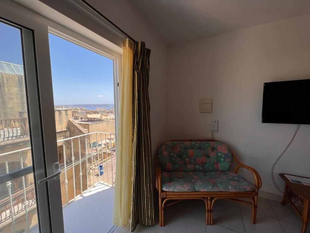 a room with a chair and a large window at All Nations Holiday Home in Għajnsielem