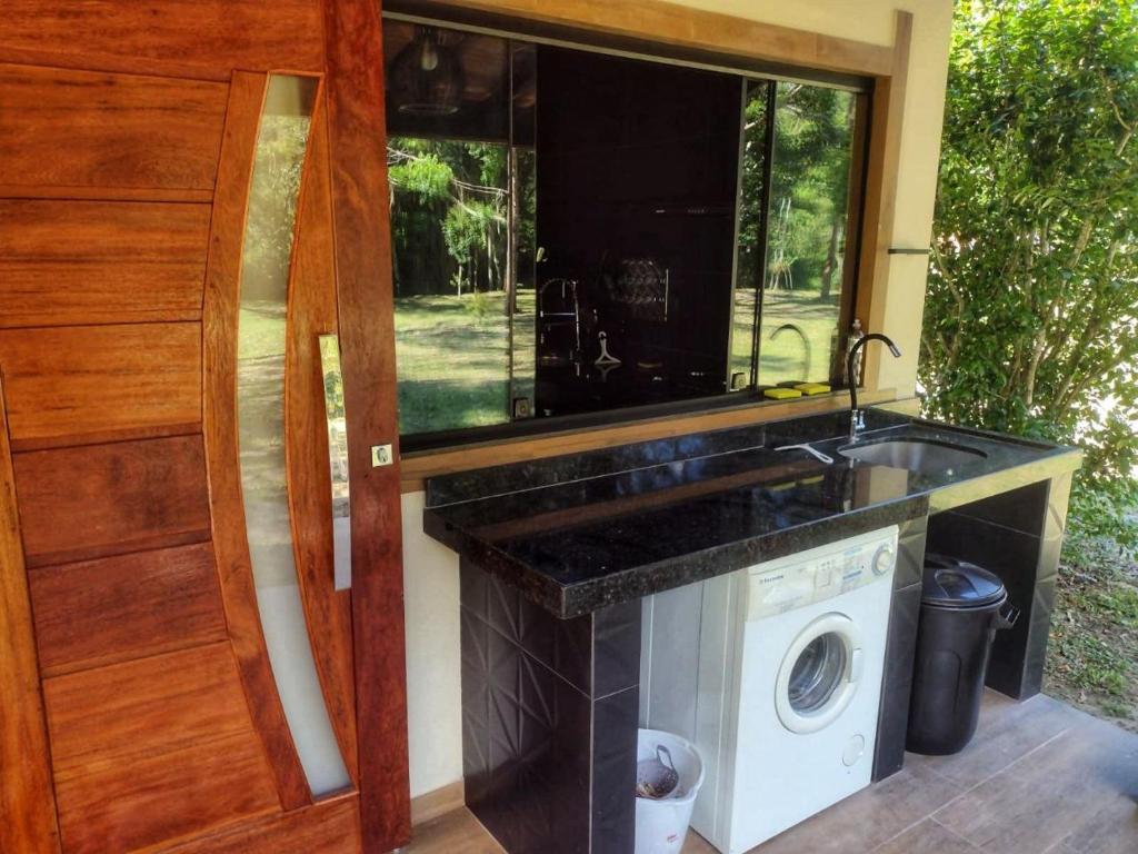 a kitchen with a sink and a washing machine at Chácara Brisa Do Rio in Nova Friburgo