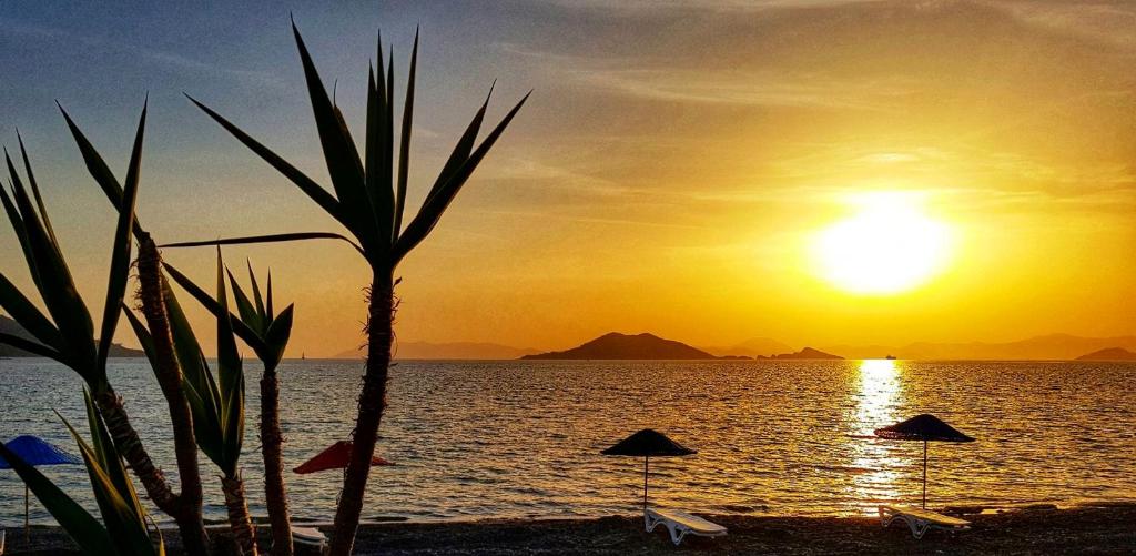 a sunset on a beach with umbrellas and the ocean at MIA CASA HOTEL in Fethiye