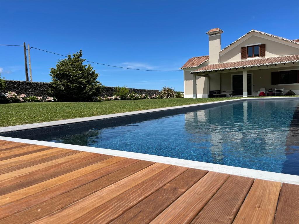 uma piscina com um deque de madeira em frente a uma casa em Azores Green Nature em Rabo de Peixe