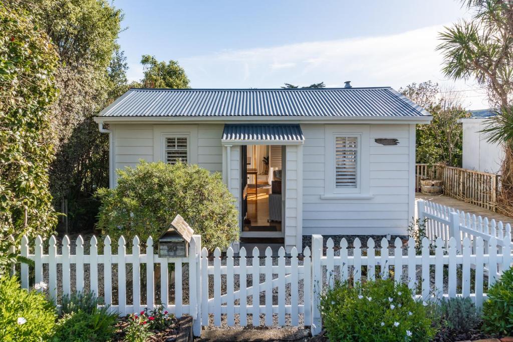 a tiny house with a white fence at Kowhai Cottage & Studio in Raglan