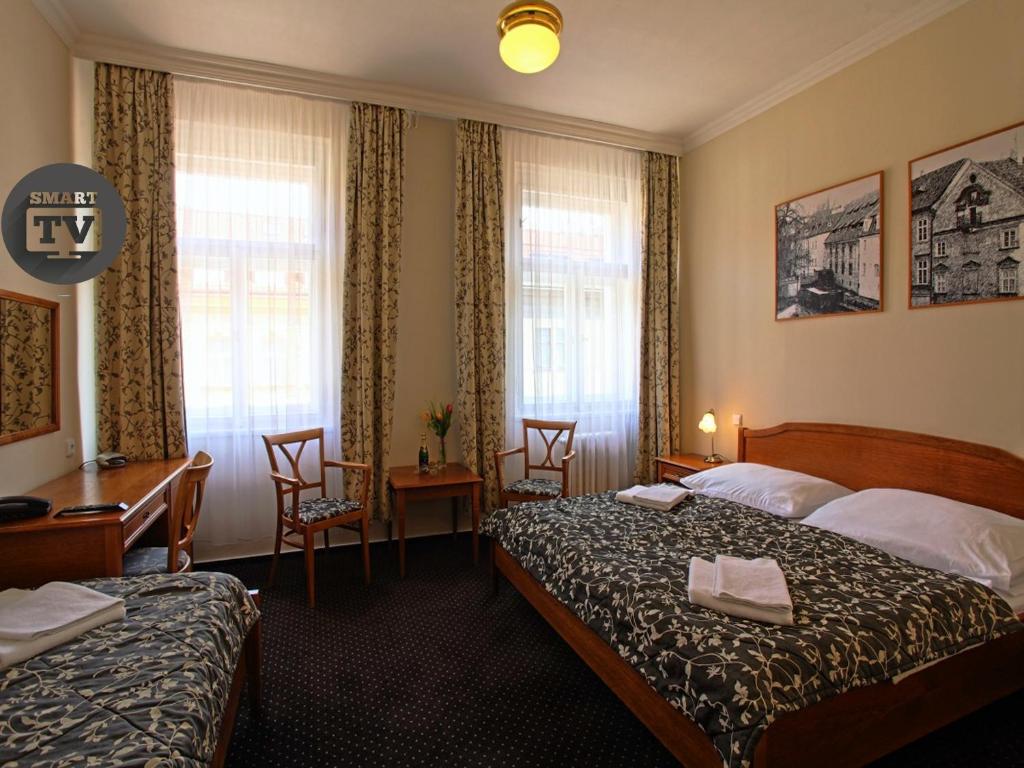 a hotel room with two beds and a desk at Anna Hotel in Prague