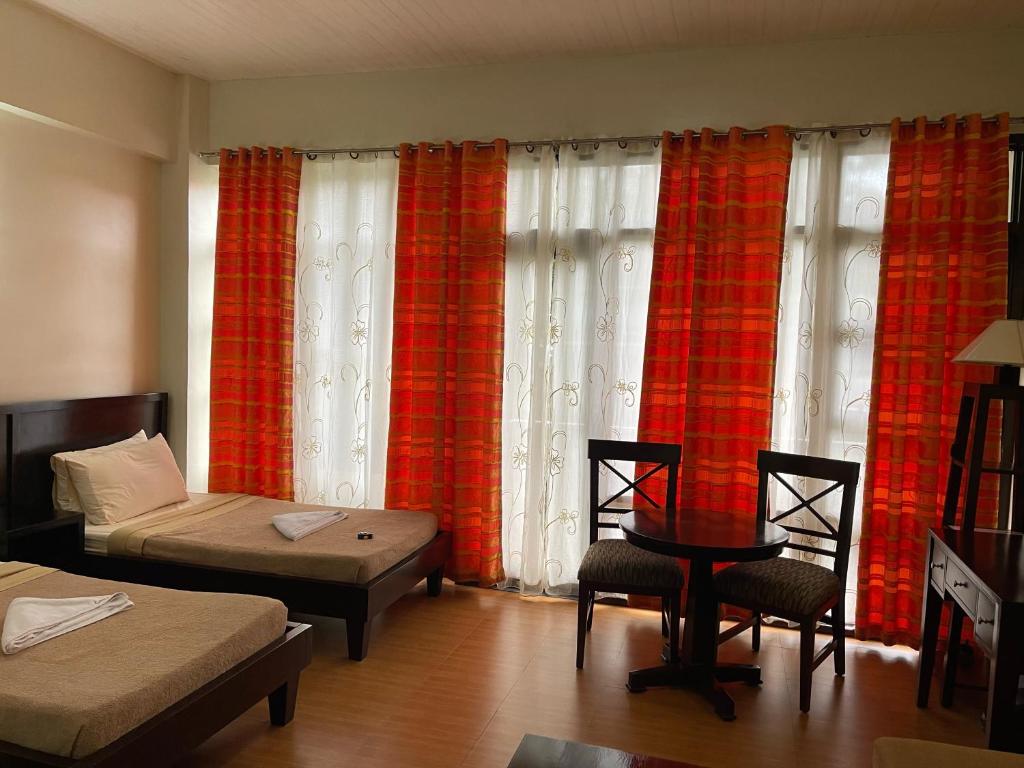Habitación con cama, mesa y cortinas. en 3 Pax Charming Foggy Cold Breeze, Cozy Gardenville Hotel, en Baguio