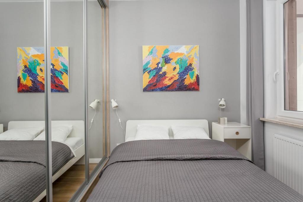 ワルシャワにあるChill Apartments Warsaw Airportのベッドルーム1室(ベッド2台付)が備わります。壁には絵画が2点飾られています。