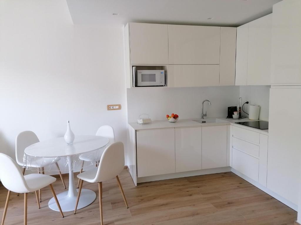 a white kitchen with a white table and chairs at La conchiglia in Rapallo
