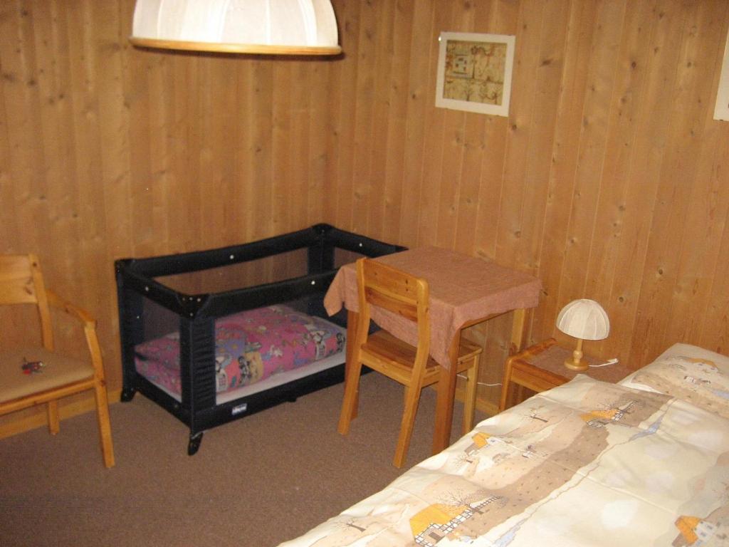 een slaapkamer met een bed, een tafel en een stoel bij Chalet Suveran 1 in Arosa