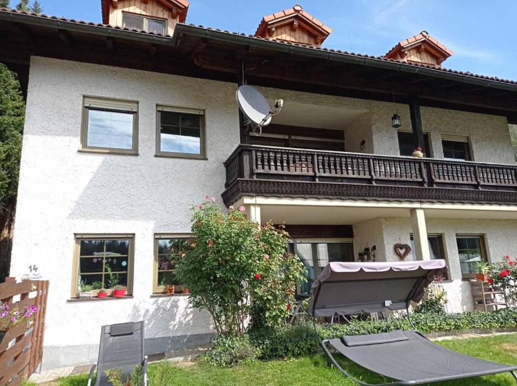 a large white house with a balcony and a table at Ferienwohnung Schmidt in Bayerisch Eisenstein