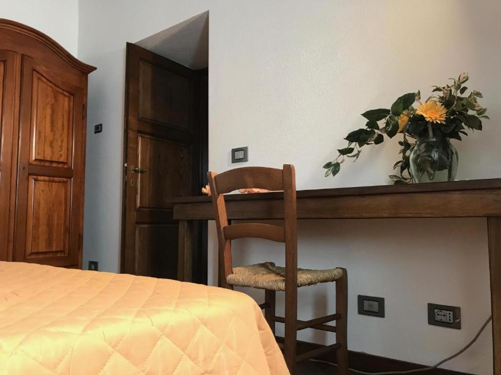 una silla sentada junto a un escritorio con un jarrón de flores en Il pianetto appartamento, en Pieve Fosciana
