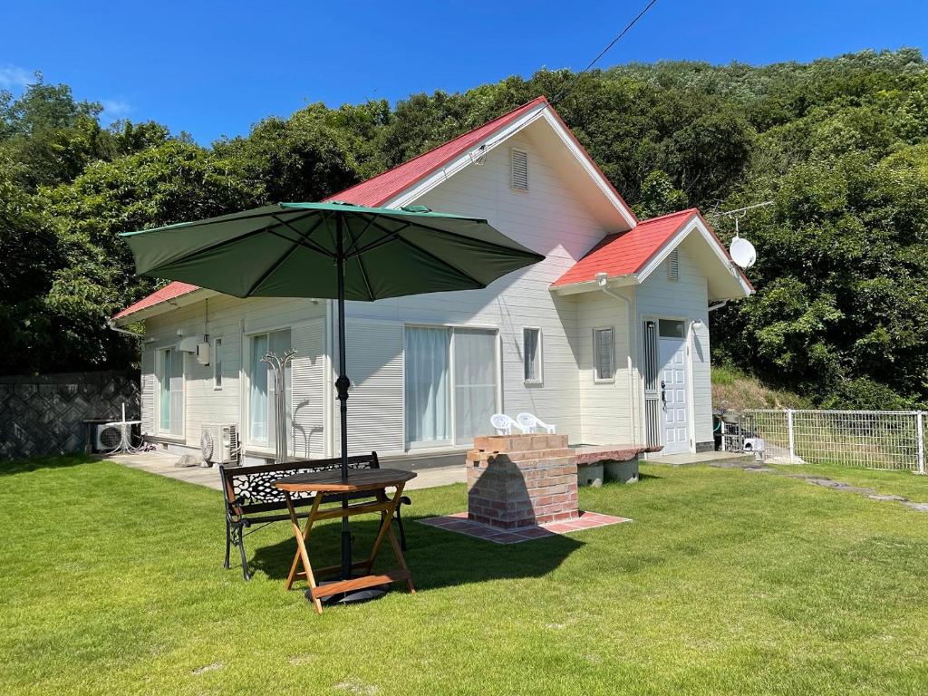 土莊町的住宿－Holiday Villa 旅生，院子里带桌子和雨伞的房子