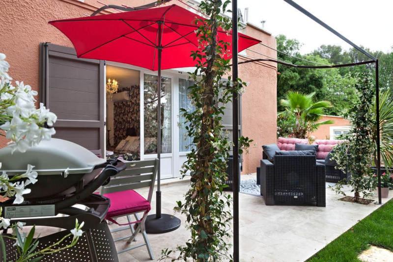 a patio with a red umbrella and a table at La Casa dei Sogni in Flayosc