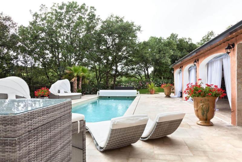 a backyard with a swimming pool with chairs and a table at La Casa dei Sogni in Flayosc