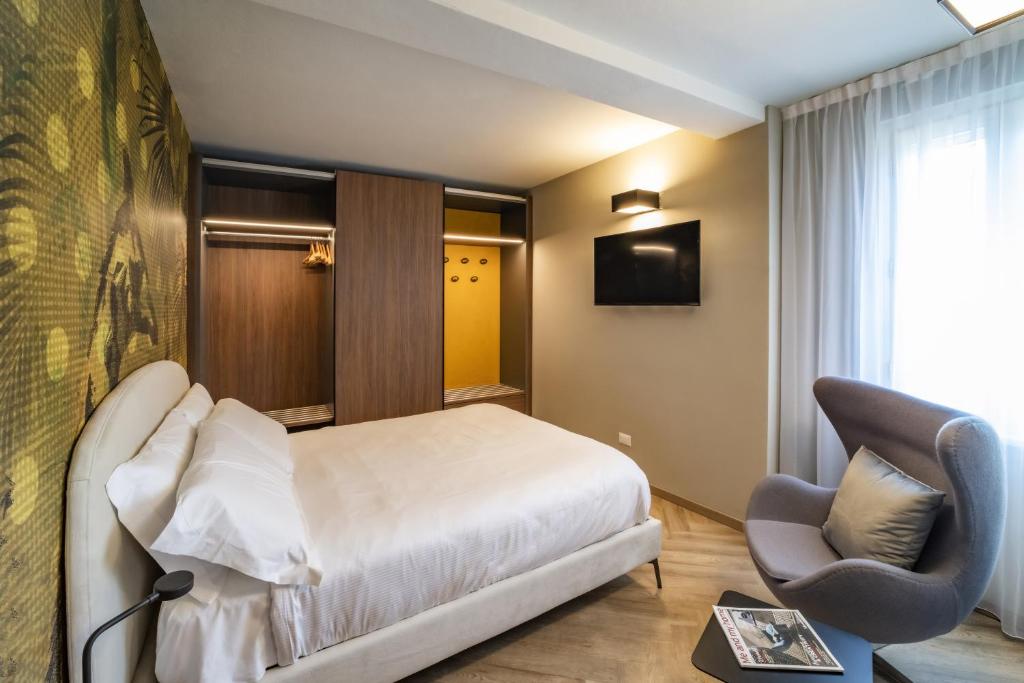 リモーネ・スル・ガルダにあるAppartamento Scalinata San Roccoのベッドと椅子付きのホテルルーム
