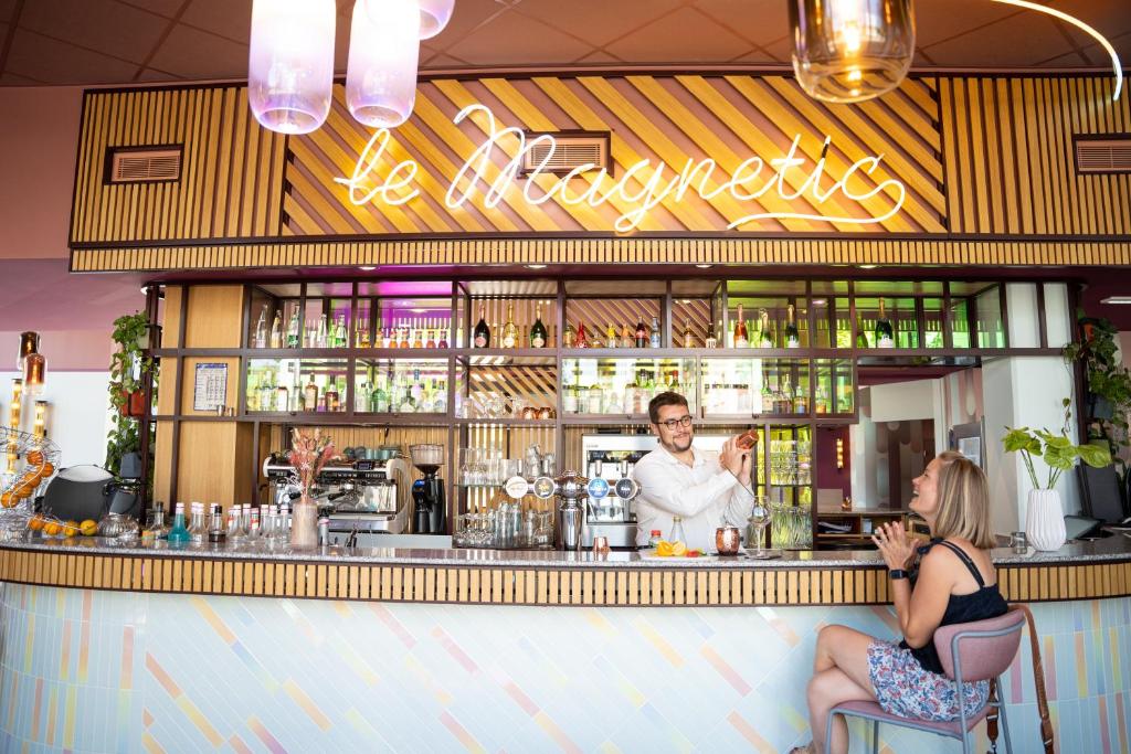 Un uomo e una donna seduti al bar di Hôtel Aiden by Best Western Clermont-Ferrand - Le Magnetic a Clermont-Ferrand