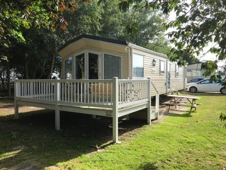 ein kleines Haus mit einer Veranda und einem Picknicktisch in der Unterkunft The Winchester luxury pet friendly caravan on Broadland Sands holiday park between Lowestoft and Great Yarmouth in Corton