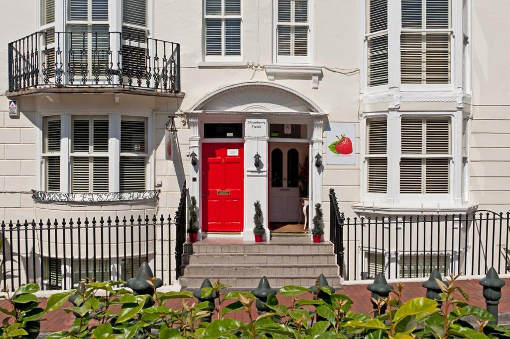 a white house with a red door and stairs at Strawberry Fields in Brighton & Hove