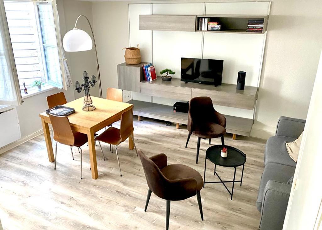 a living room with a table and chairs and a television at Vieux-Lille : Appartement de charme in Lille