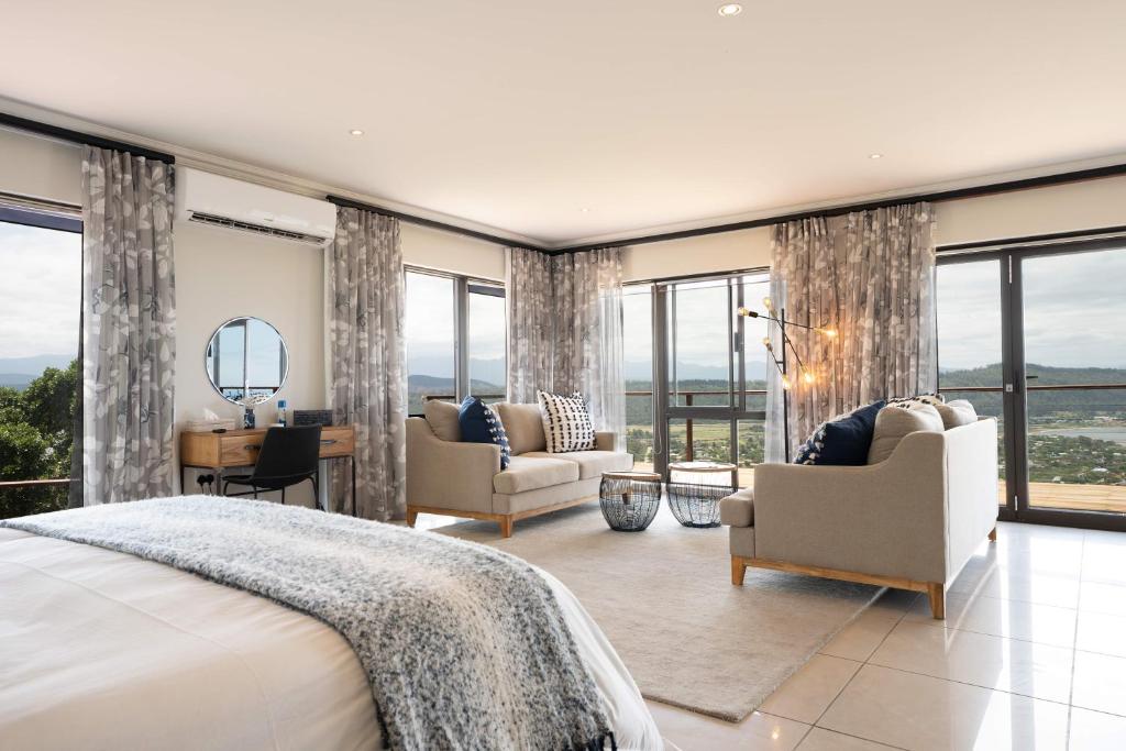 - une chambre avec un lit, des chaises et des fenêtres dans l'établissement Simbavati Fynbos on Sea, à Sedgefield