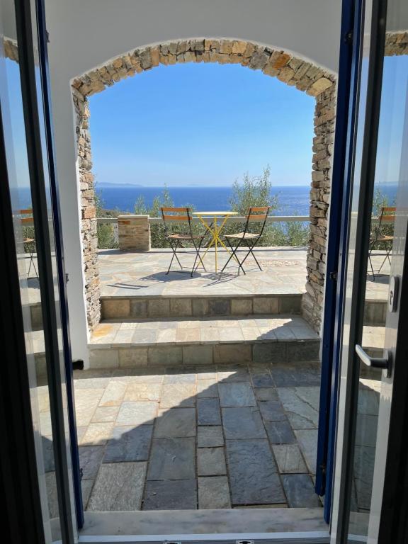 Une porte ouverte s'ouvre sur une terrasse offrant une vue sur l'océan. dans l'établissement Sea view studio 2, à Batsi