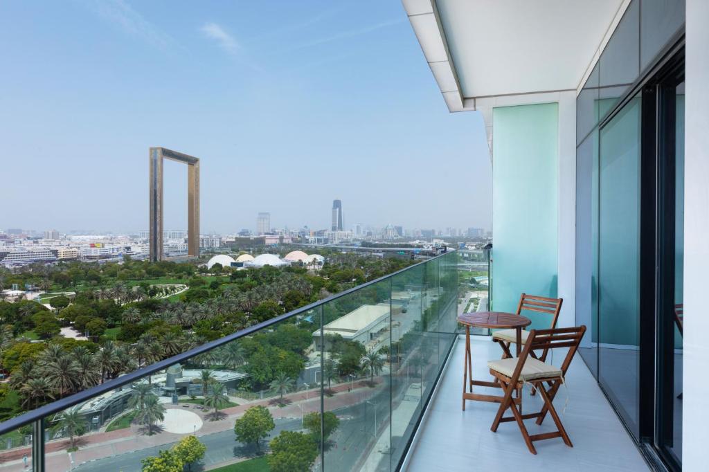 杜拜的住宿－Maison Privee - Superb 1BR apartment overlooking Zabeel Park and Dubai Frame，阳台配有两把椅子和一张桌子,享有城市美景。