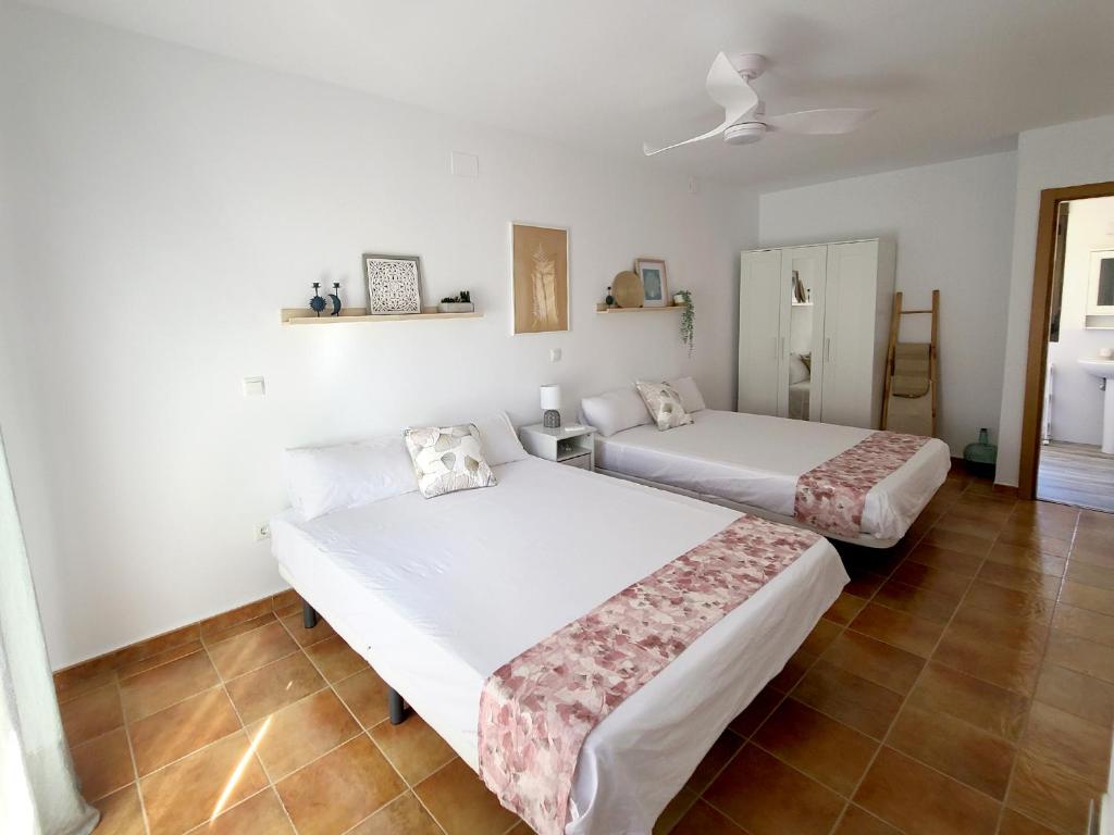 Habitación con 2 camas, paredes blancas y suelo de baldosa. en El Escondite de Gredos, en Lanzahita