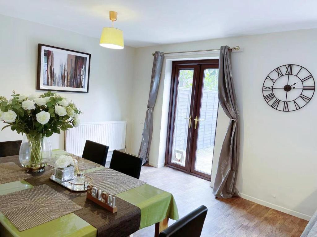 a dining room with a table and a clock on the wall at Oxford City Centre House With Parking in Oxford