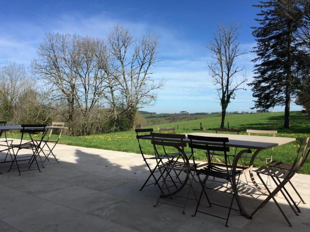 a group of tables and chairs with a field at La Ferme bio de la Salvanié in Bellegarde
