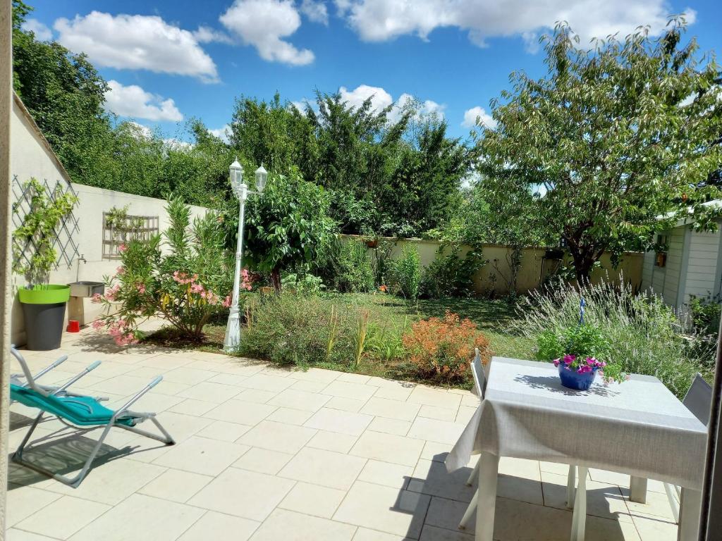 eine Terrasse mit einem Tisch und Stühlen im Garten in der Unterkunft Le jardin d'Anatole in Bourges