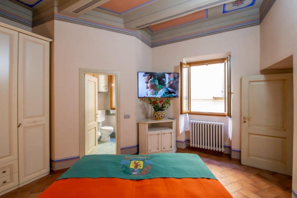 um quarto com uma cama e uma televisão na parede em IBibiena -SUITE CASA FIORITA em Bibbiena