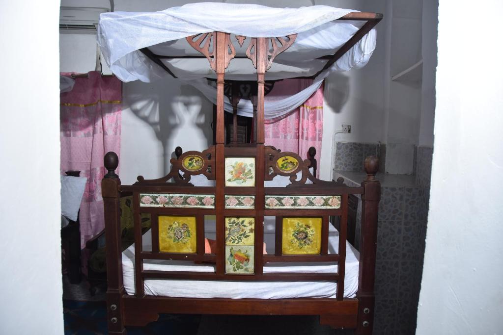 Cette chambre comprend un lit à baldaquin en bois. dans l'établissement BABAbora house, à Ngambo