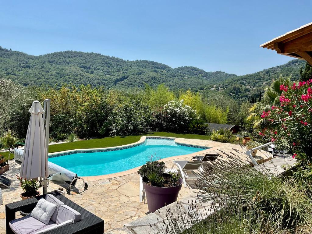 a swimming pool with an umbrella and chairs and trees at Mas Giro in Le Bar-sur-Loup