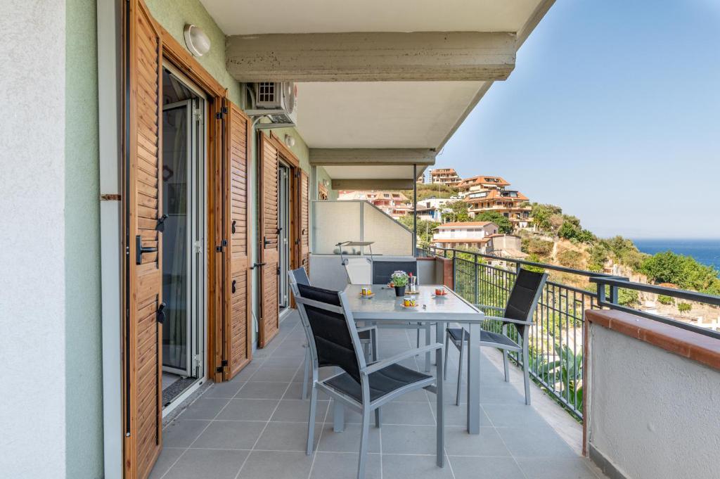 balcón con mesa, sillas y vistas al océano en Casa Azzurra - Sea View Apartment, en Letojanni