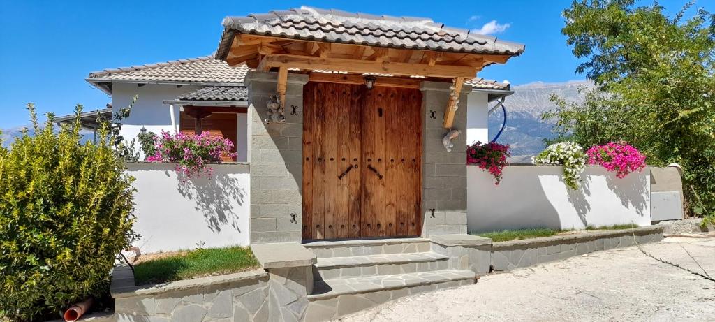 una piccola casa bianca con una porta in legno di B Vishe Guest House a Gjirokastër