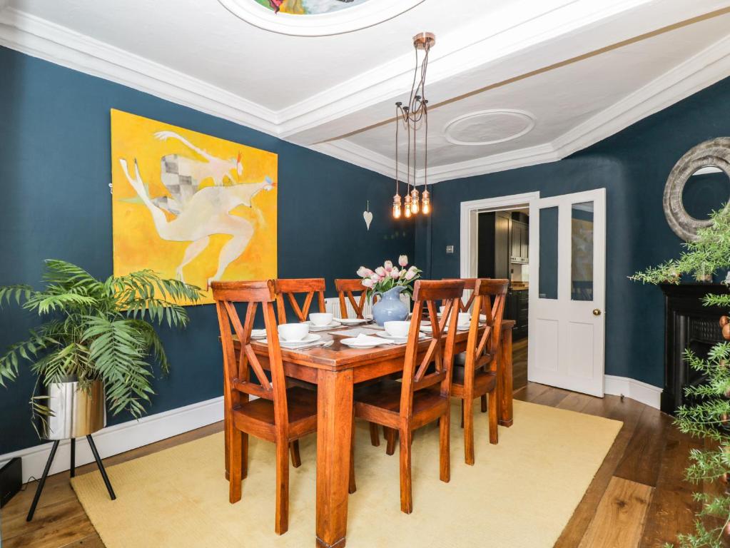 a dining room with blue walls and a wooden table and chairs at Cuckoo Cottage in Worcester