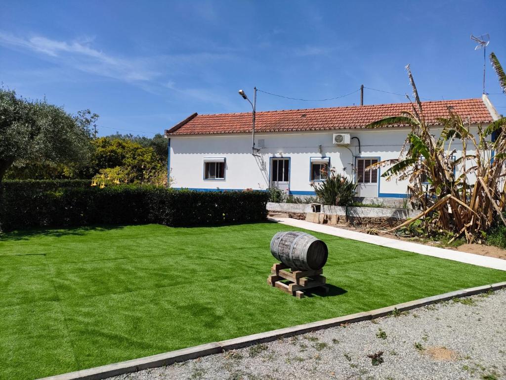 ein Haus mit einem Rasen mit einem Fass im Hof in der Unterkunft Monte da Vinha Nova in Santiago do Cacém