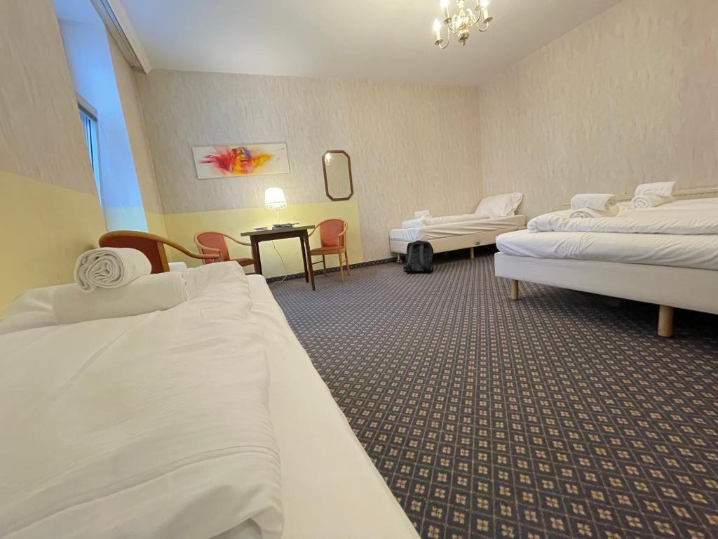a hotel room with three beds and a table at Hotel Tabor Rooms in Vienna