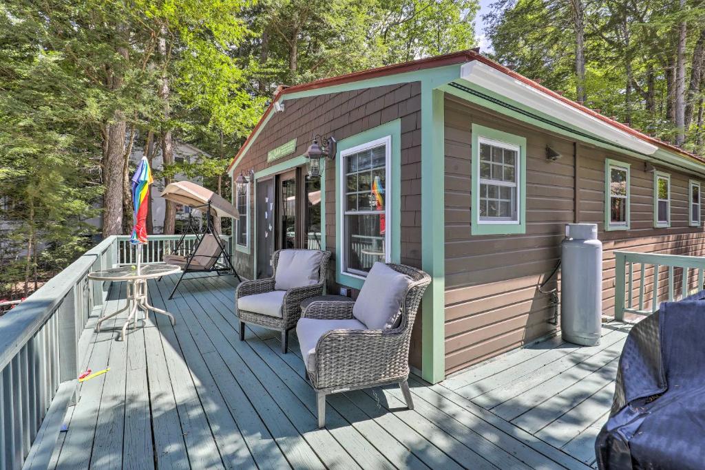 a small cabin with two chairs and a table on a deck at Lake Hermit Cabin with Kayaks and Paddleboards! in Sanbornton