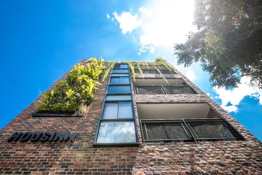 a tall brick building with windows with plants on it at Housinn co-living Fatima en Medellín in Medellín