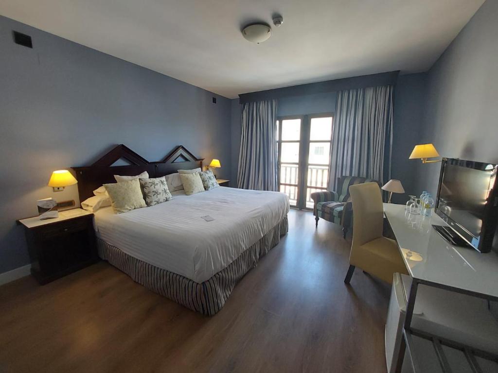 烏貝達的住宿－RL烏韋達城市酒店，一间卧室配有一张床和一张书桌及电视