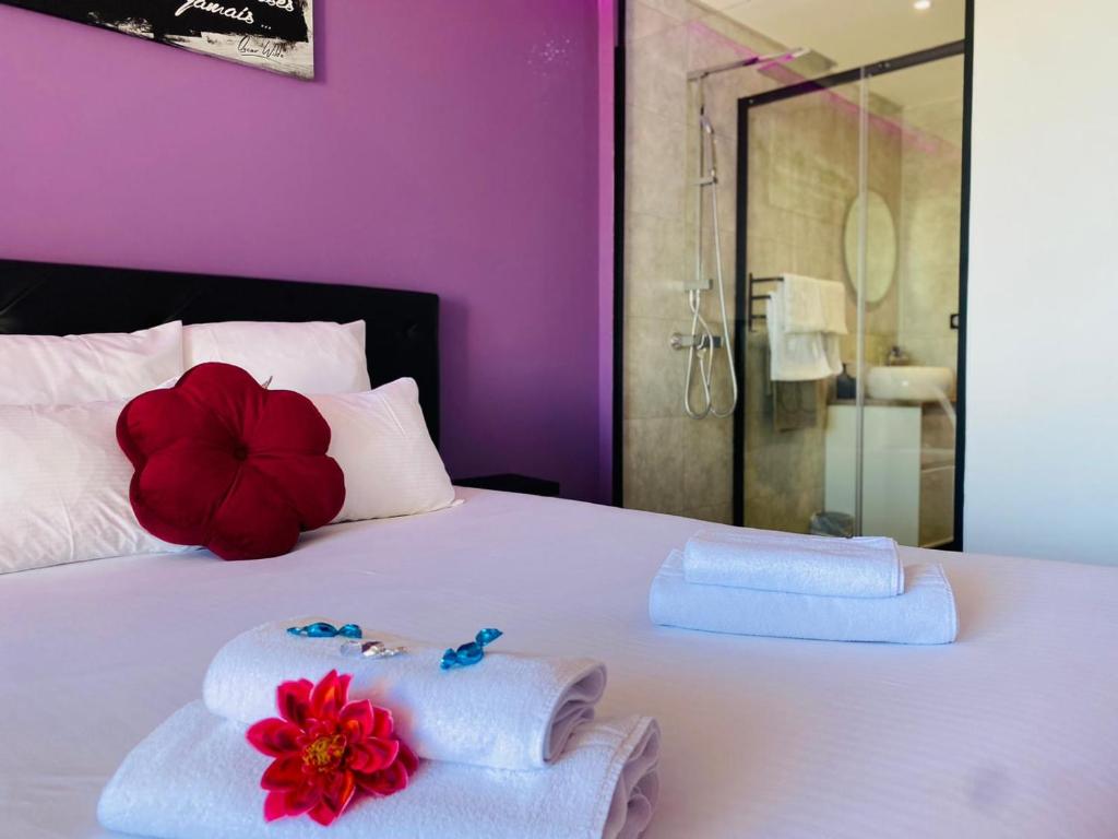 a white bed with towels and a red flower on it at STUDIO CAMP NATURISTE VUE MER, le Gilyves cocooning in Cap d&#39;Agde