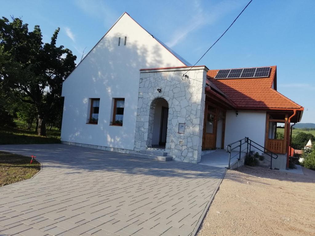 un pequeño edificio blanco con techo rojo en Zempléni Tündérkert vendégház en Füzérkomlós