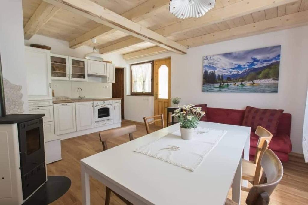 een keuken en een woonkamer met een witte tafel en stoelen bij Apartma Mlekuž in Bovec