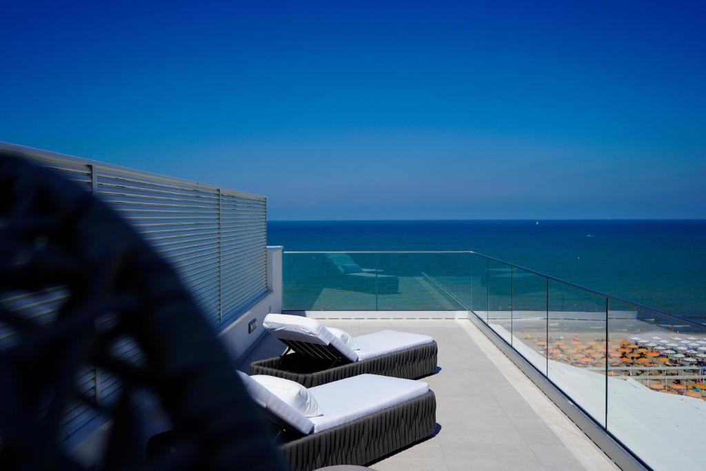 a balcony with chaise lounges and the ocean at Hotel Arizona in Riccione